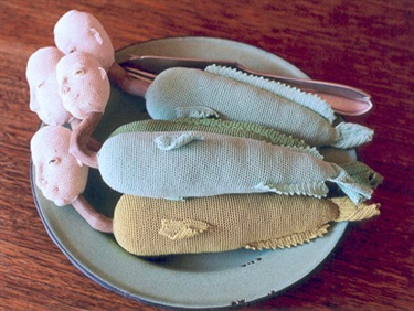 Catherine Hearse, Young Fish People Prepared for Supper, cotton, wood, glass beads, EPNS cutlery, enamel plate, 52 x 27 x 10 cm. Courtesy of Legge Gallery.